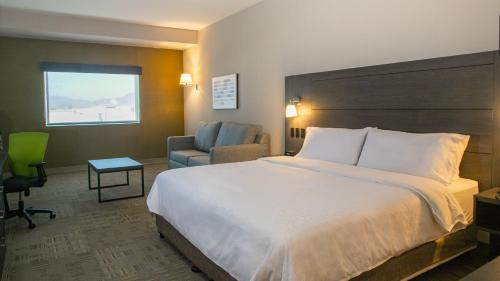 a hotel room with a large bed and a chair at Holiday Inn Express & Suites - Tijuana Otay by IHG in Tijuana