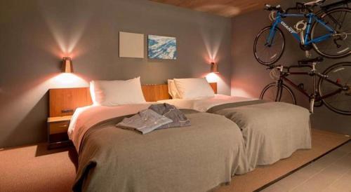 a bedroom with two beds with a bicycle on the wall at Hotel Cycle in Onomichi