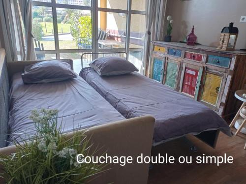- 2 lits dans une chambre avec un canapé et une fenêtre dans l'établissement Cap Esterel Rez de jardin D2, à Saint-Raphaël