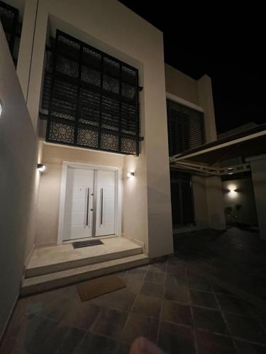 a white door on the side of a building at night at فيلا ضاحية الرمال 2 in Riyadh
