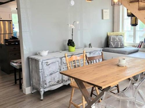 uma sala de jantar com uma mesa de madeira, uma mesa e cadeiras em Om chalet 1 avec spa face au fleuve em Saint-Jean