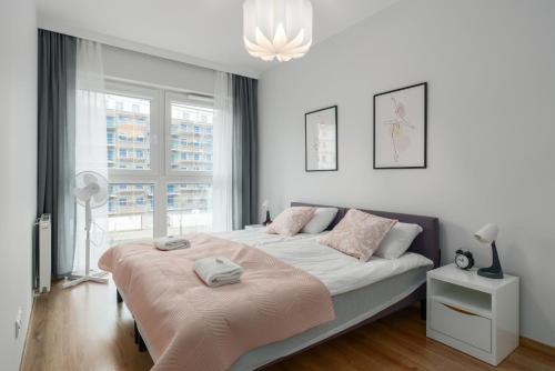 a white bedroom with a large bed and a window at Lwowska Apartment by the Malta Lake Poznań by Renters in Poznań
