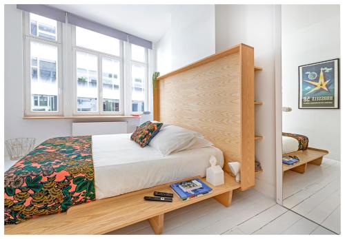 a bedroom with a bed with a wooden headboard and windows at Happy guesthouse in Brussels