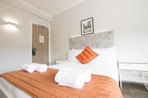 a bedroom with a large bed with orange and white pillows at Westciti Caroco Aparthotel in Croydon