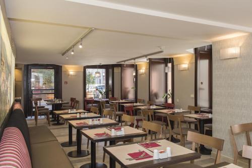 a restaurant with tables and chairs and windows at Three Corners Hotel Art in Budapest