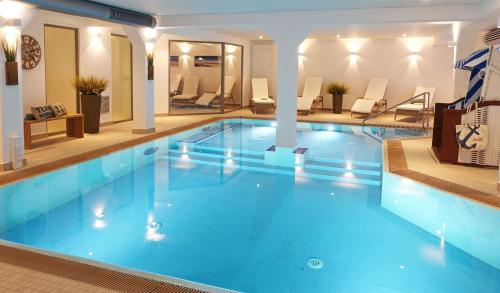 a large swimming pool with blue water in a building at Inselresidenz Strandburg Juist - Wohnung 107 (Ref. 52044) in Juist