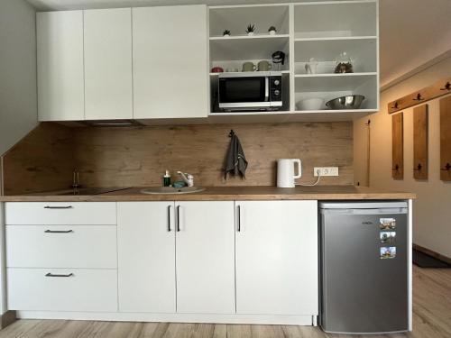 a kitchen with white cabinets and a stainless steel refrigerator at Apartamenti Jēkabpilī in Jēkabpils
