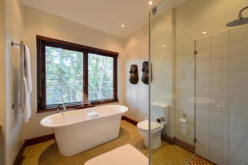 Un baño con bañera, inodoro y ducha de cristal. en San Lameer Villa 5910 - 4 Bedroom Luxury - 8 pax - San Lameer Rental Agency, en Southbroom