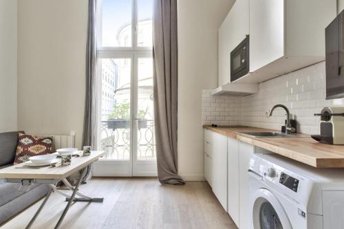 une cuisine avec une machine à laver et une table dans l'établissement Studio Vivienne - Welkeys, à Paris