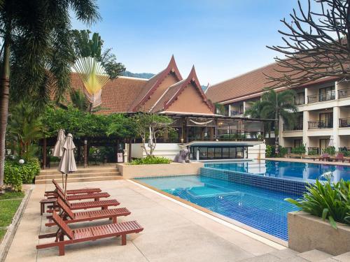 a swimming pool with lounge chairs next to a hotel at Deevana Patong Resort & Spa in Patong Beach