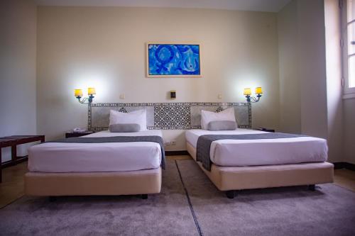 a bedroom with two beds and a painting on the wall at Hotel Continental Luanda in Luanda