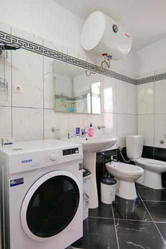 a washing machine in a bathroom with a sink and a toilet at Villa All Season in Sarandë