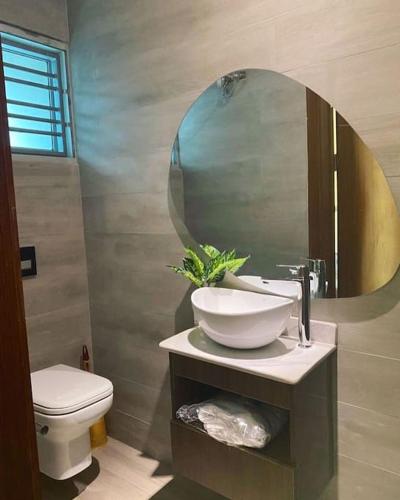 a bathroom with a sink and a mirror and a toilet at Lovely 2 bedroom in ikate in Lekki