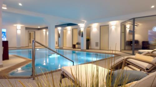 a large swimming pool in a building with chairs at Inselresidenz Strandburg Juist - Turmwohnung 205 (Ref. 50959) in Juist