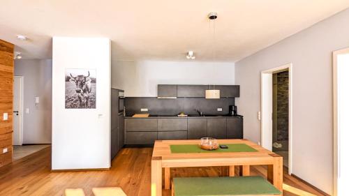 a living room with a wooden table and a kitchen at Chalet am Breitenberg Appartement CB 11 in Pfronten