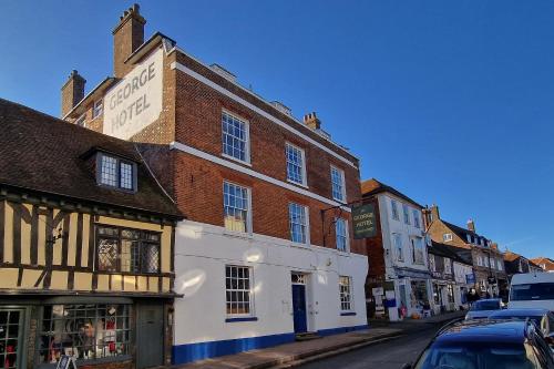 a street with buildings and cars parked on the street at The George Hotel in Battle