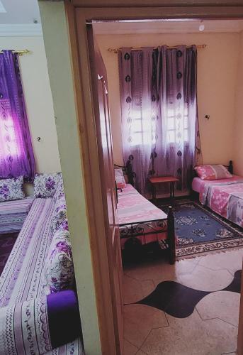 um pequeno quarto com duas camas e uma porta em Ben lahbib em Khenifra