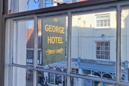 a window with a sign that reads the george hotel at The George Hotel in Battle
