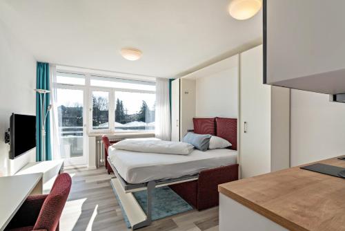 a small bedroom with a bed and a kitchen at Huber Living Basic 105 in Germering