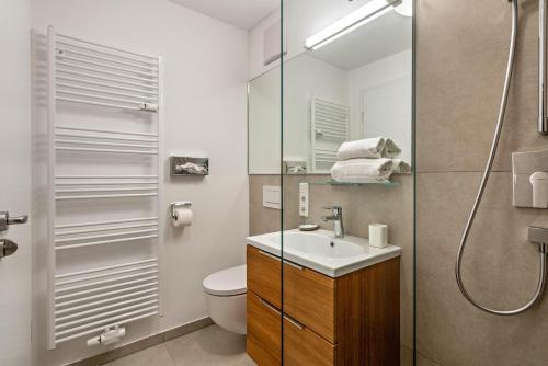 a bathroom with a toilet and a sink and a shower at Huber Living Basic 105 in Germering