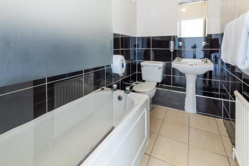 a bathroom with a tub and a toilet and a sink at The George Hotel in Battle