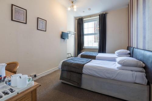 a hotel room with two beds and a window at The George Hotel in Battle