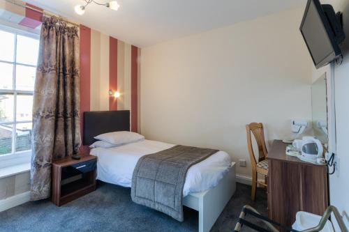 a hotel room with a bed and a window at The George Hotel in Battle