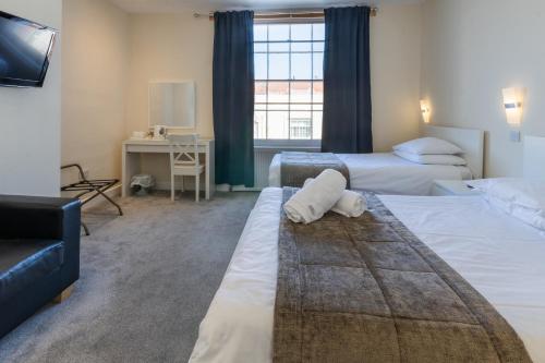 a hotel room with two beds and a television at The George Hotel in Battle