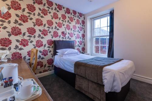 a bedroom with a bed and a table and a window at The George Hotel in Battle