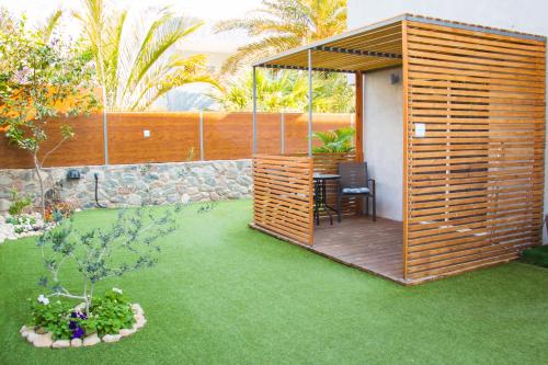 a garden with a wooden pergola and a table on a lawn at Stacey’s Stylish studio in Eilat