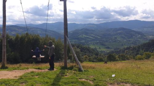 a man standing on a swing in the mountains at Садиба Федорчуків Гірська хатина in Sheshory