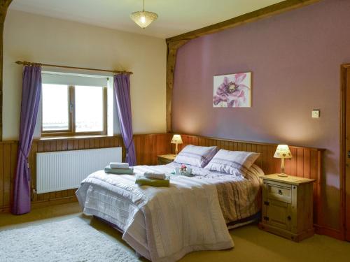 a bedroom with a bed with purple walls and a window at The Old Stables in Freethorpe
