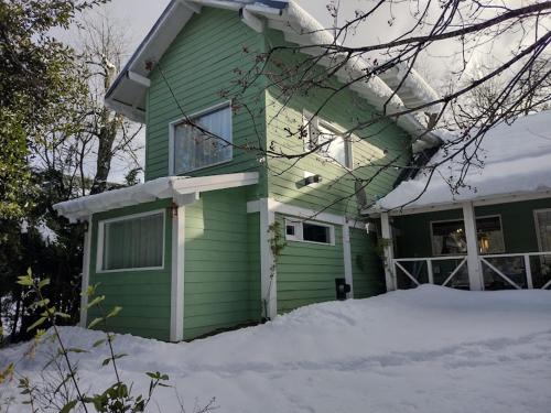 a green house with snow in front of it at El Recuerdo in Villa La Angostura
