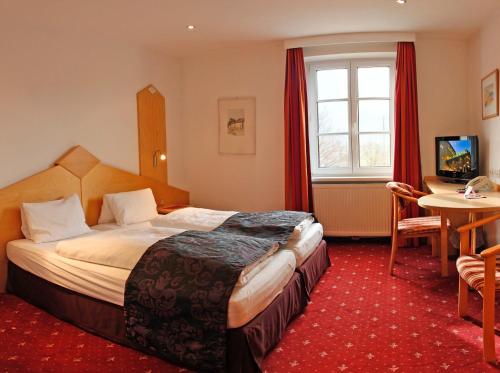 ハル・イン・チロルにあるオーストリア クラシック ホテル ハイリグクロイツのベッドとテーブルが備わるホテルルームです。