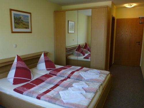 a hotel room with a bed with red and white pillows at Hotel am Stadtwald in Stralsund