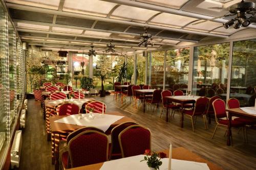a restaurant with tables and red chairs and windows at Hotel am Stadtwald in Stralsund