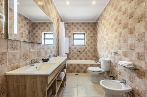 een badkamer met 2 wastafels, een toilet en een bad bij Cabo de Sagres -2 bedroom apartment in Sagres