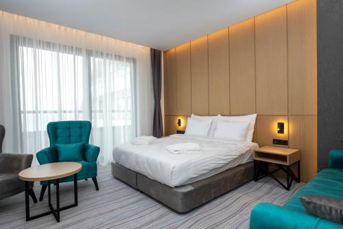 a hotel room with a bed and a blue chair at The Grandeur Hotel in Batumi