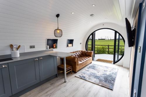 eine Küche und ein Wohnzimmer mit einem Sofa und einem Tisch in der Unterkunft The Lodge @Quarrywood in Tenby
