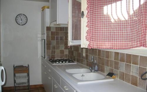a kitchen with a sink and a clock on the wall at "villa mona" a 700 m de la mer in Grimaud