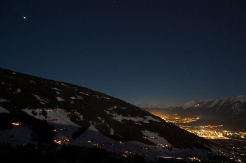 a snow covered mountain at night with a city at Austria Classic Hotel Heiligkreuz in Hall in Tirol