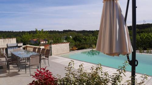 - une terrasse avec une table et un parasol à côté de la piscine dans l'établissement La chouette en provence, à Brue-Auriac