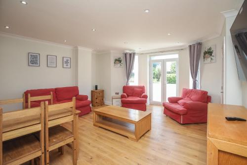 a living room with red chairs and a table at Riverside 2 Bedroom Central Kingston Flat in Kingston upon Thames
