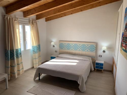 a bedroom with a large bed and a window at Domu Quesada in San Giovanni Suèrgiu