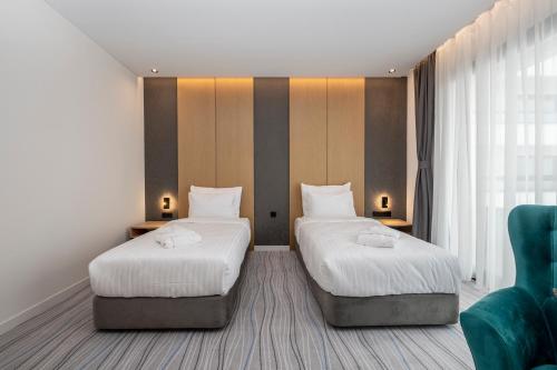 a hotel room with two beds and a green chair at The Grandeur Hotel in Batumi
