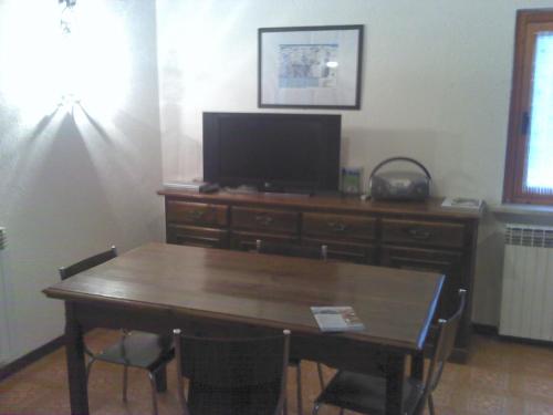 a dining room table with a television and a wooden dresser at Hermitage in Prato Nevoso