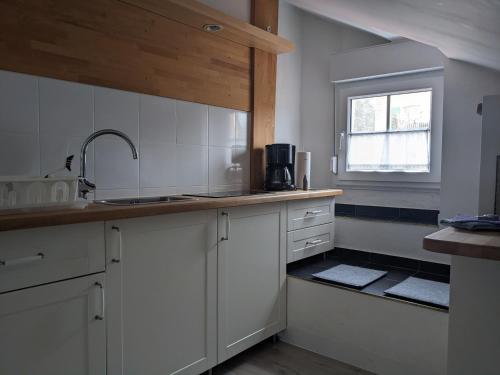 a kitchen with white cabinets and a sink and a window at Urlaub im Kunstatelier in Runkel