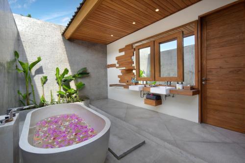 a bathroom with a bath tub with flowers in it at Ponte Villas in Gili Trawangan