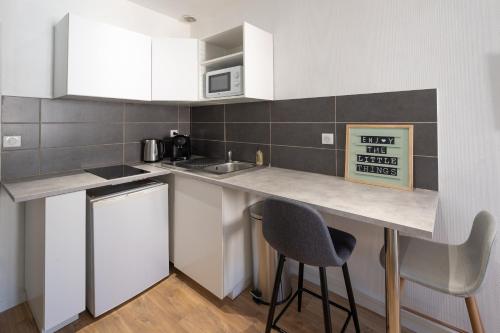 - une cuisine avec un comptoir, 2 chaises et un évier dans l'établissement Le 
