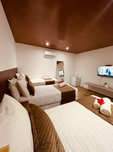 a hotel room with three beds and a flat screen tv at Refúgio da Rita in Fernando de Noronha